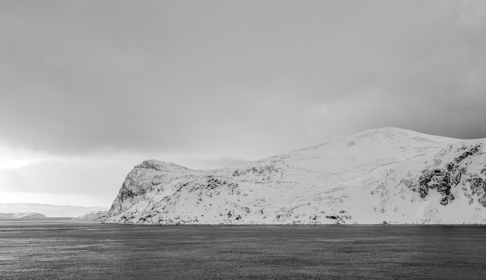 a mountain covered in snow next to a body of water