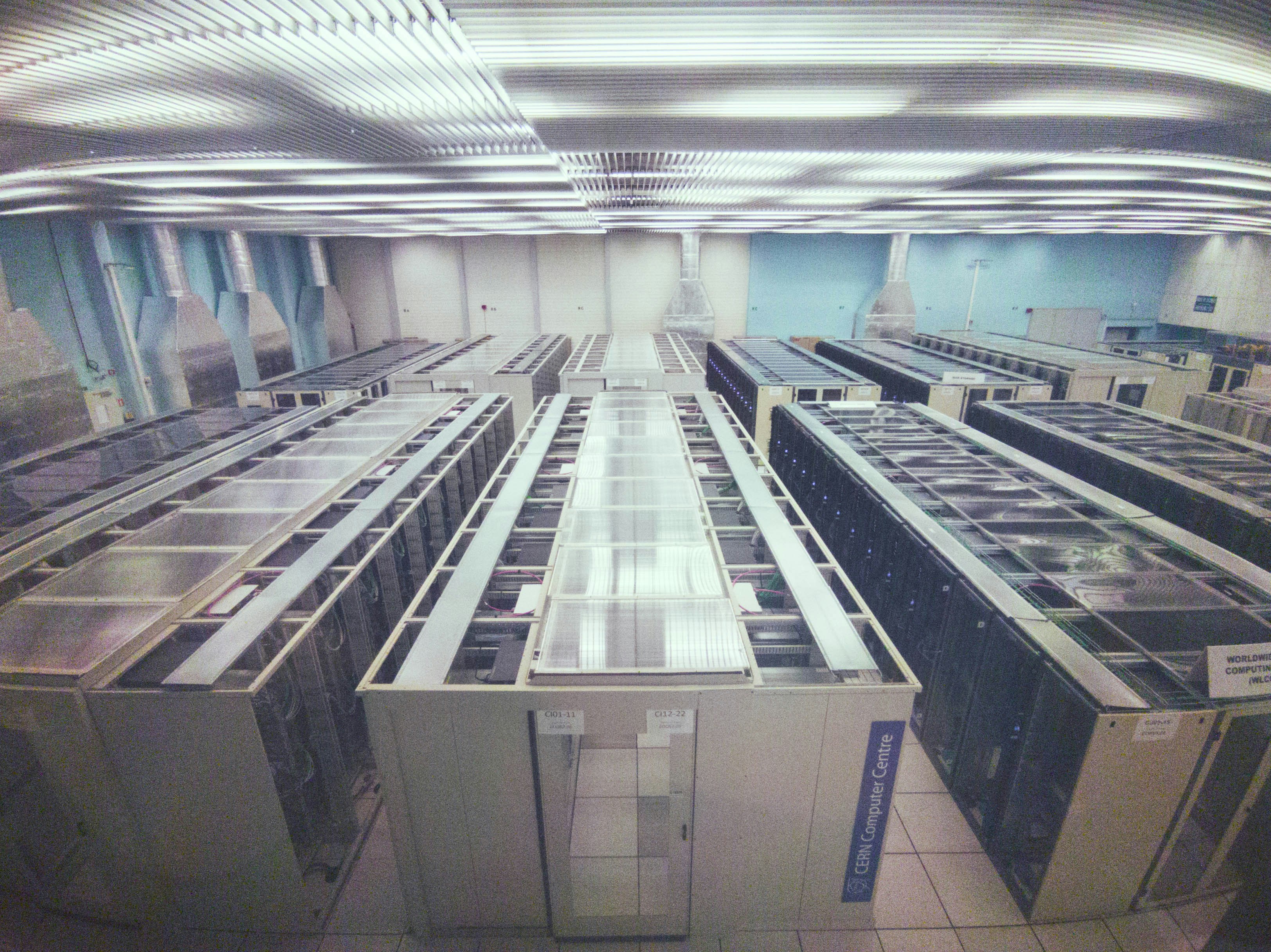 Dark server room with blue LED lighting, rows of rack-mounted servers, deep shadows and reflective floor