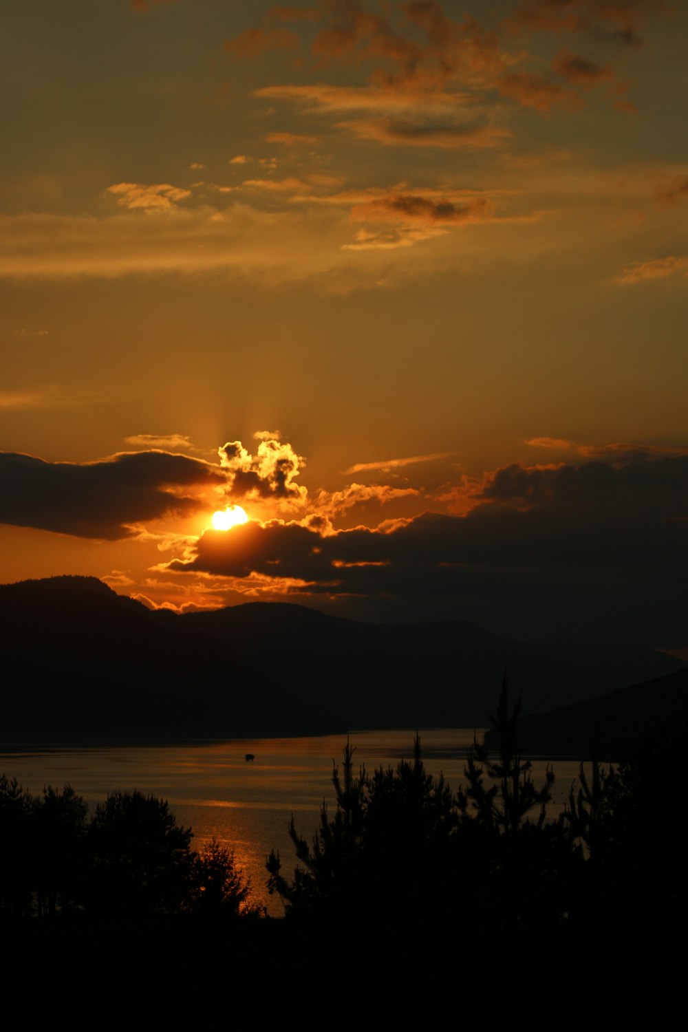 Die Sonne geht über einem See mit Bergen im Hintergrund unter