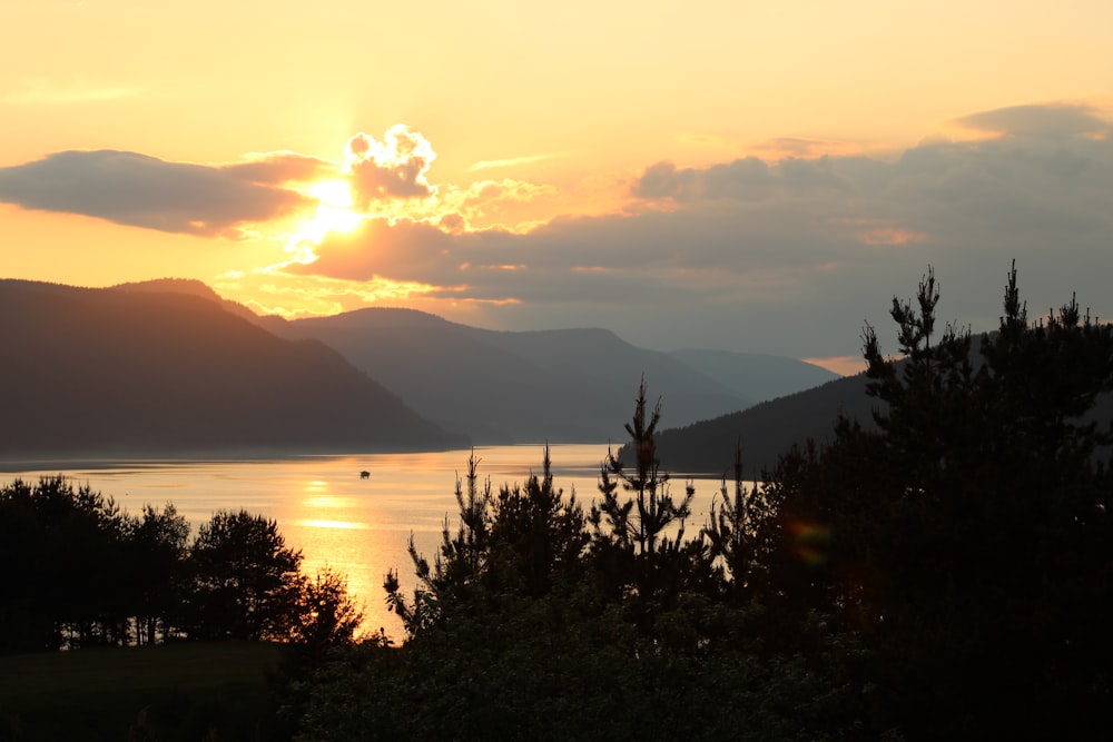 Die Sonne geht über einem See mit Bergen im Hintergrund unter