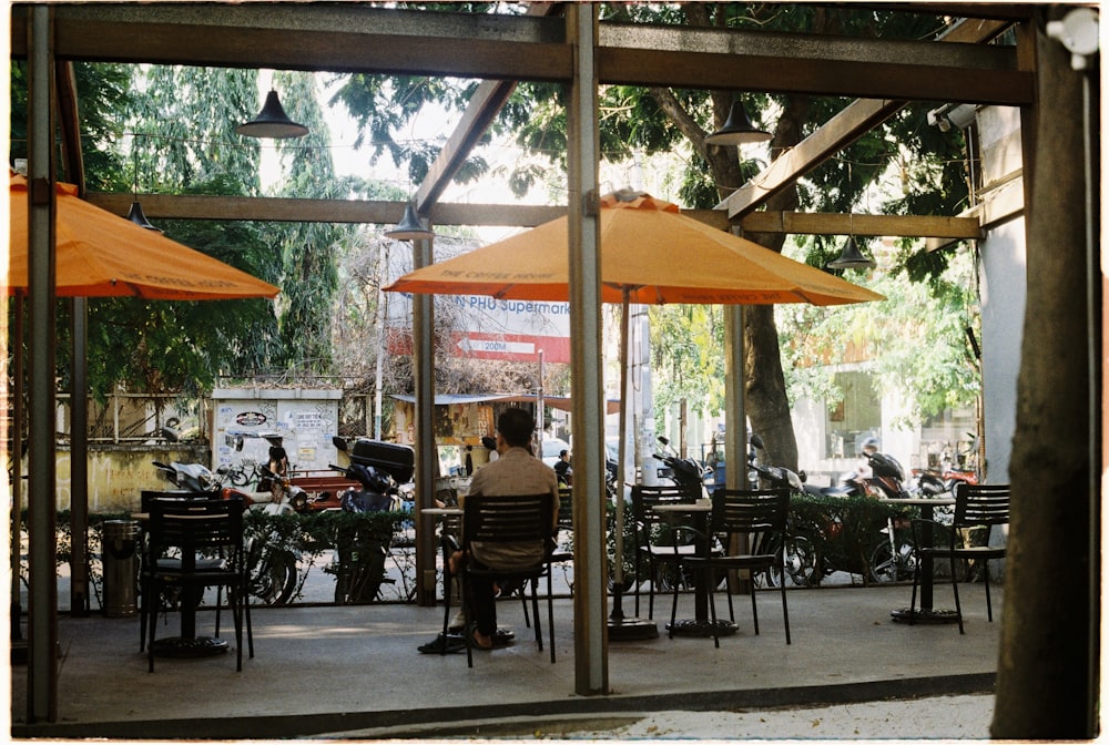 a person sitting at a table under an umbrella