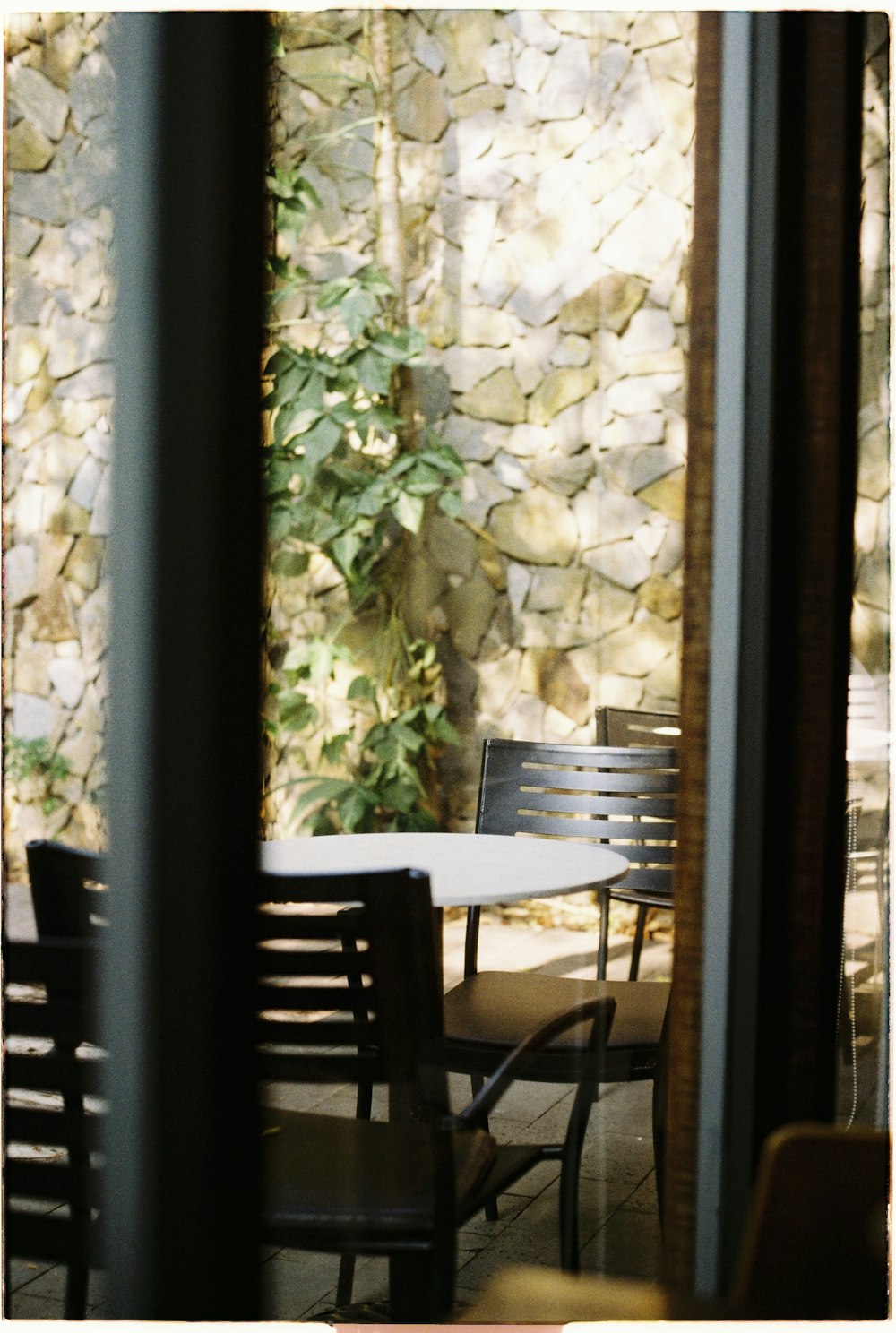 a table and chairs in front of a stone wall