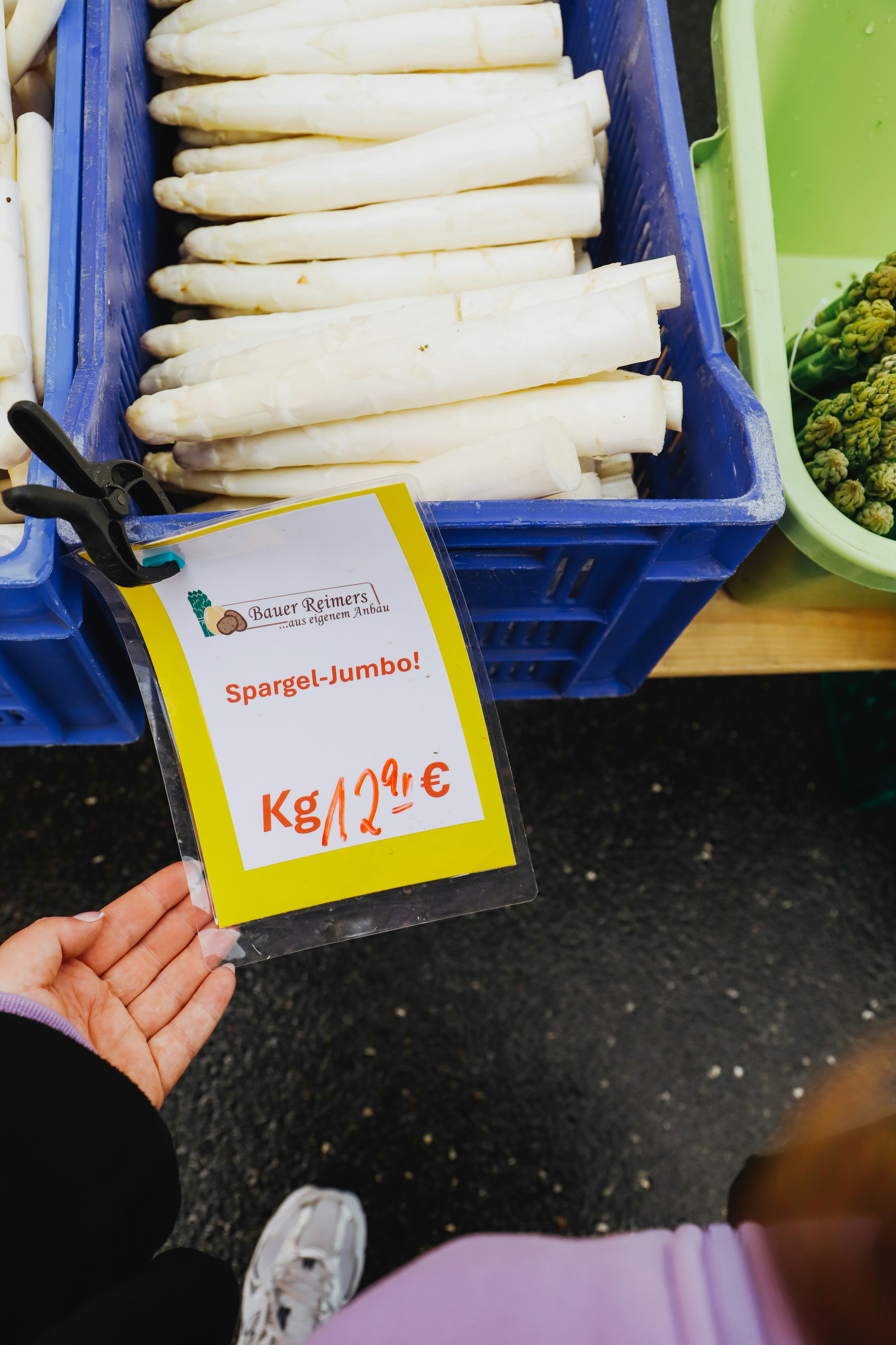 una persona sosteniendo un cartel frente a un manojo de verduras