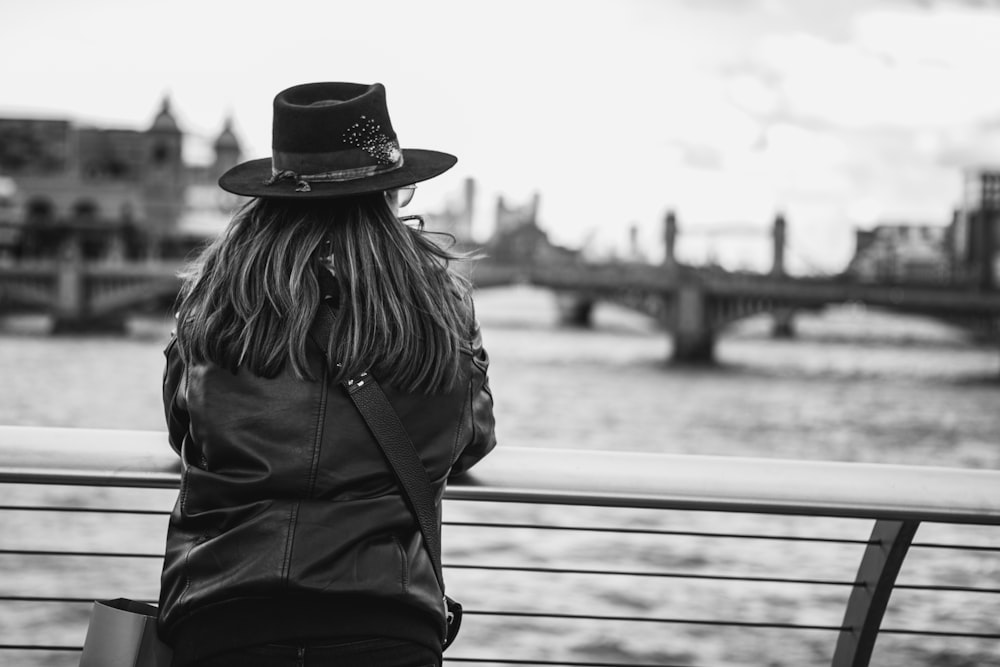 a woman wearing a hat looking out over the water