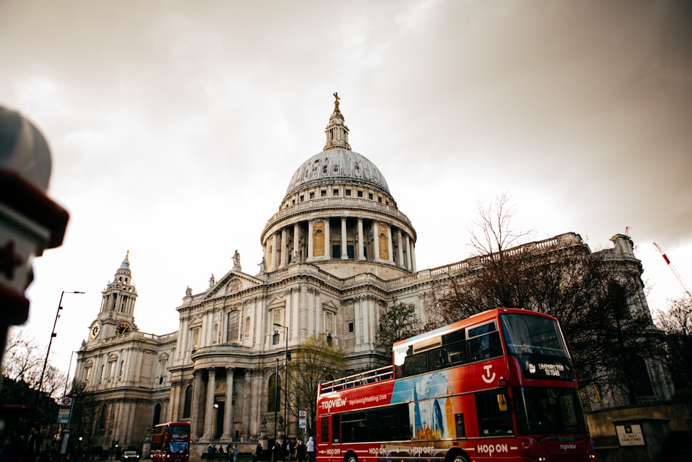 a red double decker bus parked in front of a building