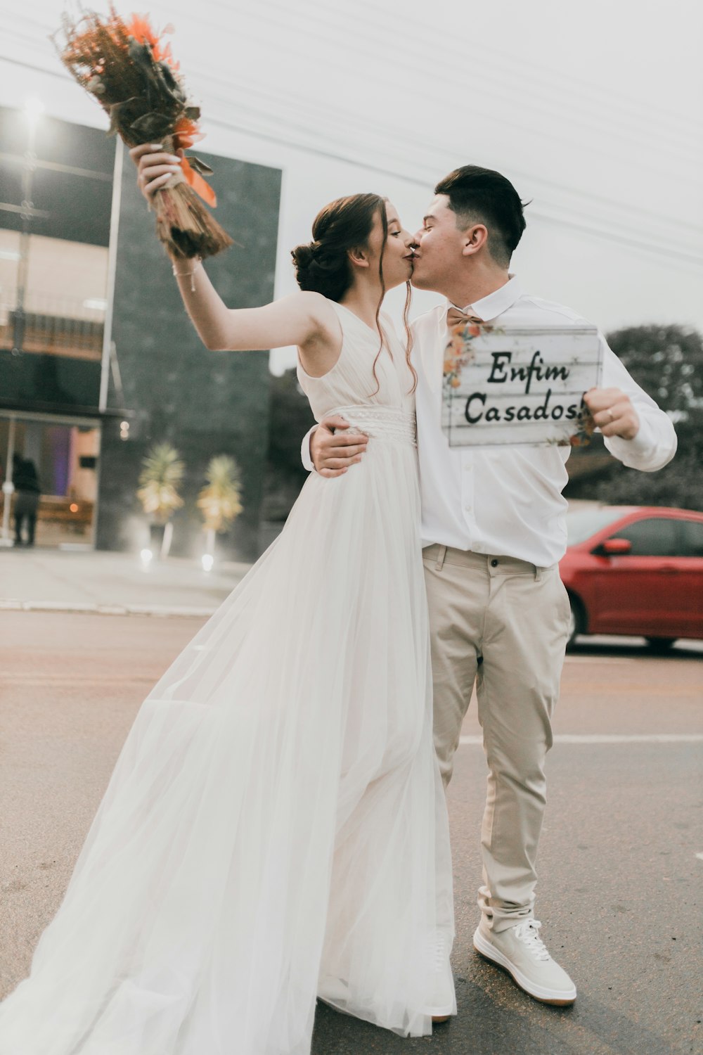 a bride and groom kissing in the middle of the street
