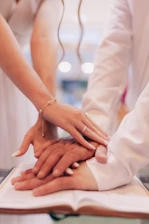 a group of people putting their hands on top of a book