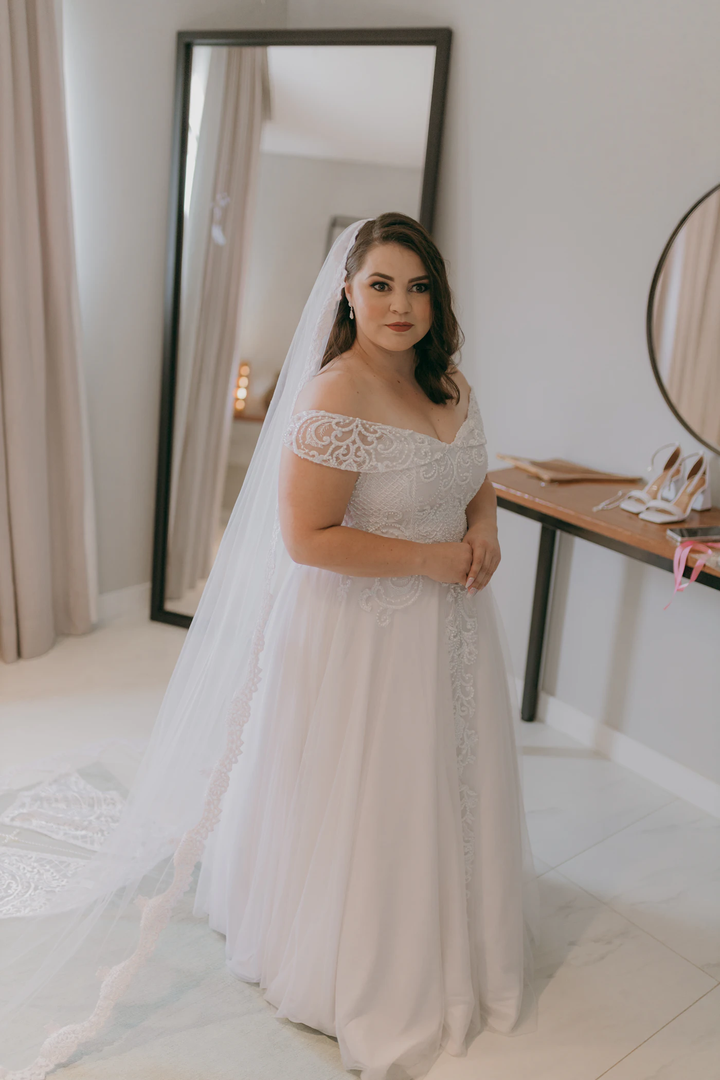 Inclusive size charts for bridal boutiques near me — A bride in a fitted gown trying on veils at a boutique