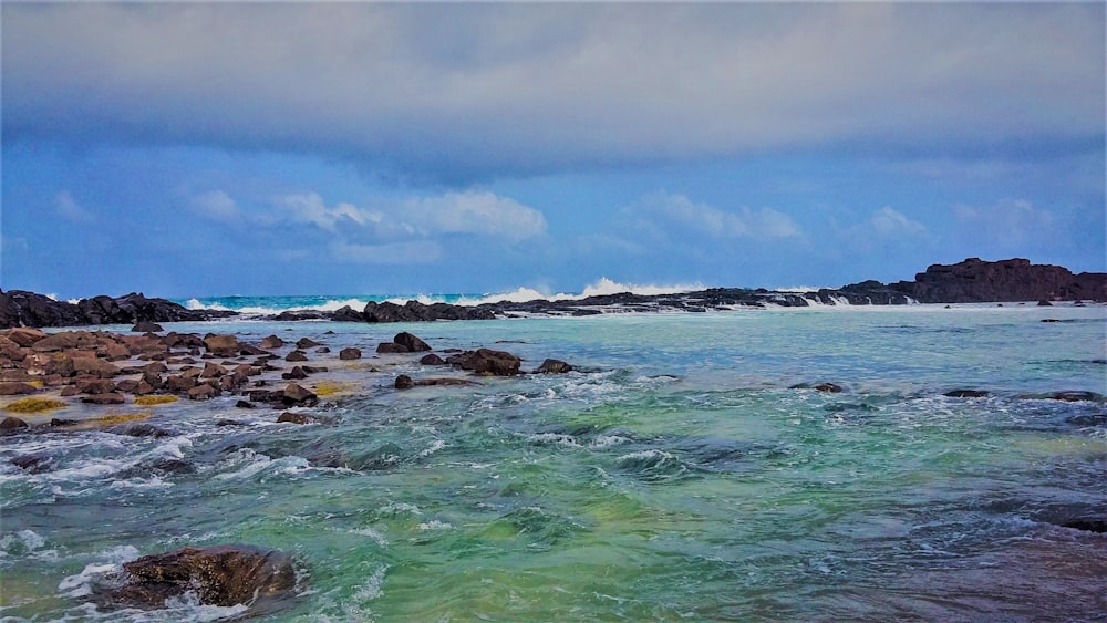 a body of water surrounded by rocks under a cloudy sky