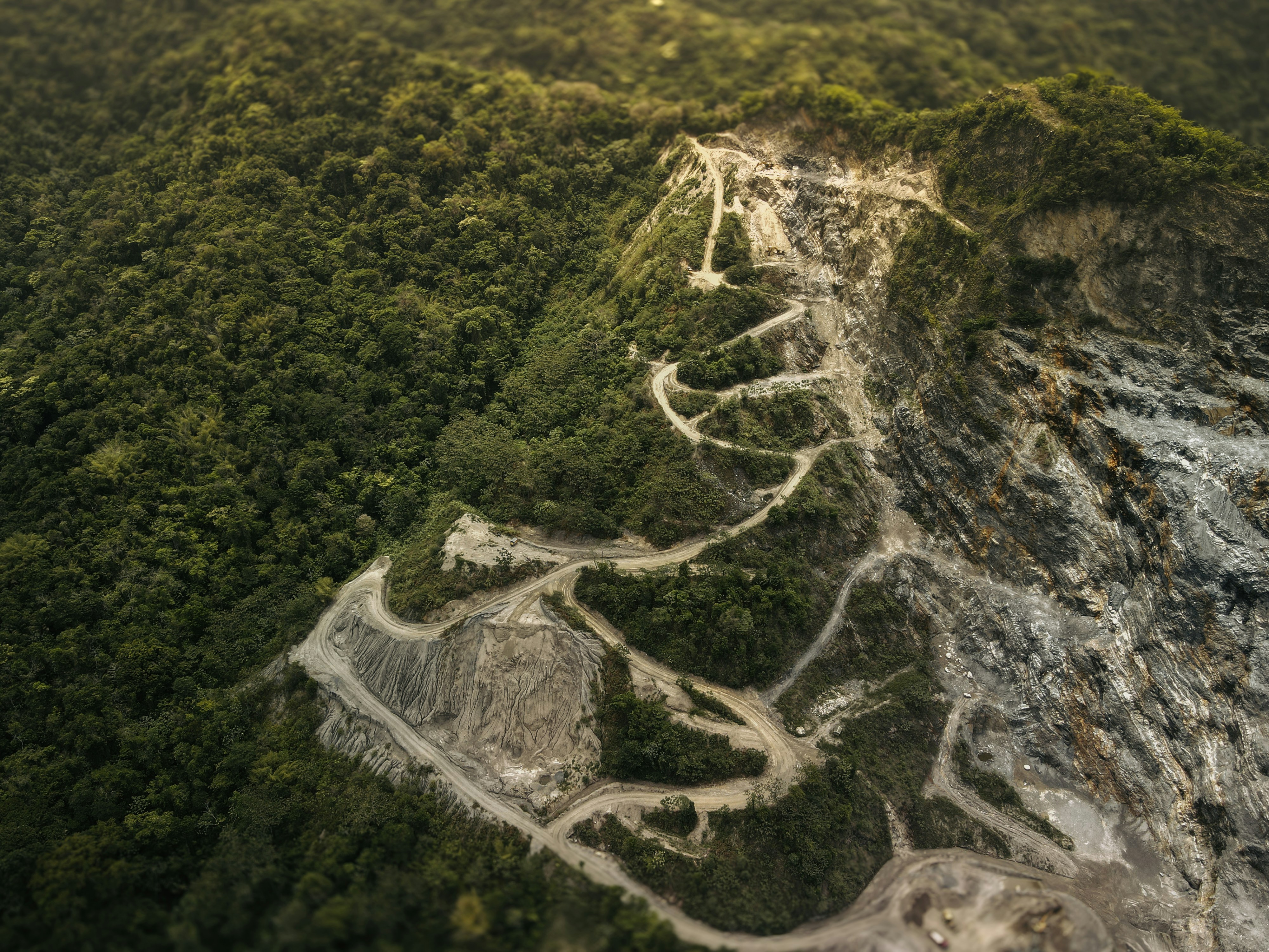 an aerial view of a winding road in the middle of a forest