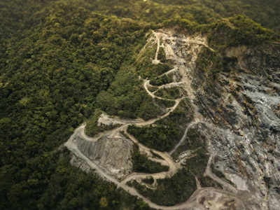 an aerial view of a winding road in the middle of a forest