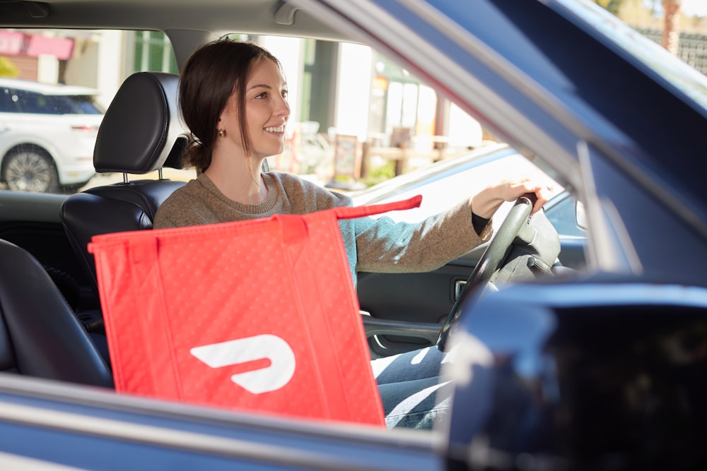 female driving with a DoorDash delivery bag