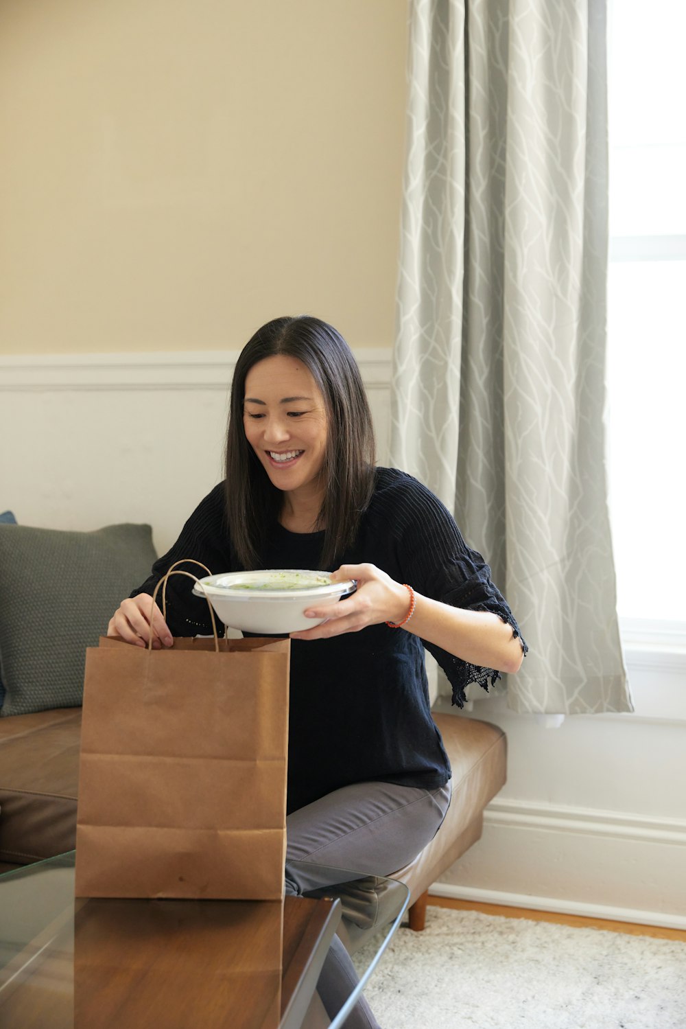woman removing takeout food from brown paper bag