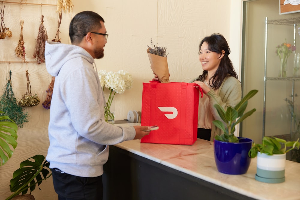 Frau verpackt Blumen in DoorDash-Tasche im Blumenladen