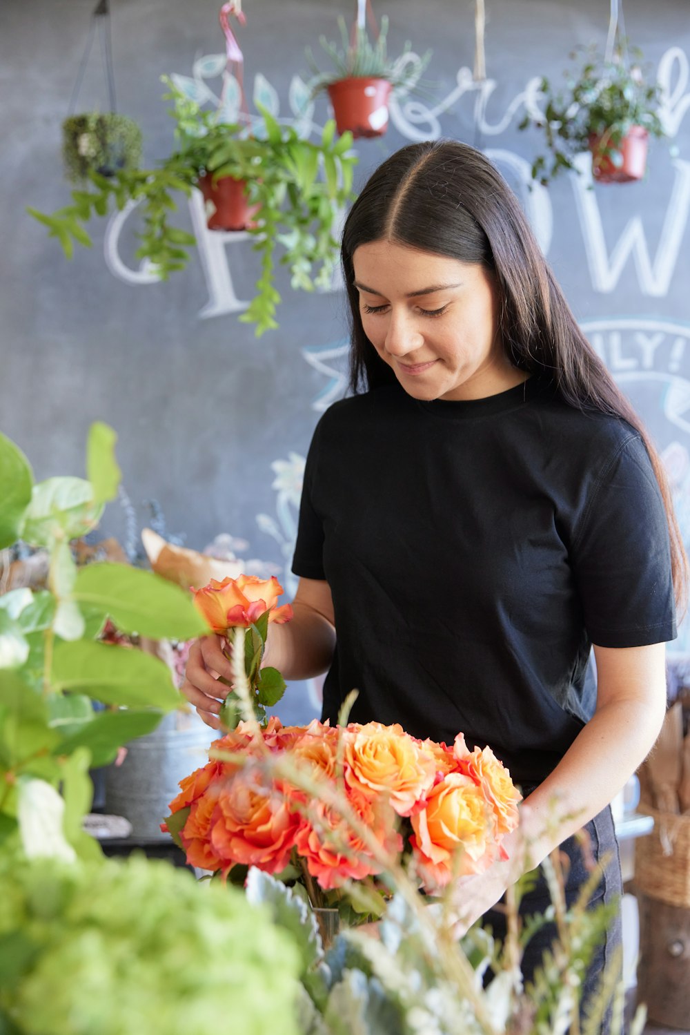 花屋でオレンジ色の花を生ける女性