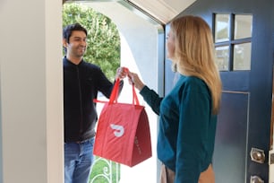 mujer recibiendo una entrega de DoorDash en la puerta principal