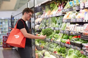 male browsing fresh produce at store with DoorDash bag
