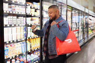 hombre navegando por productos refrigerados en la tienda con bolsa DoorDash