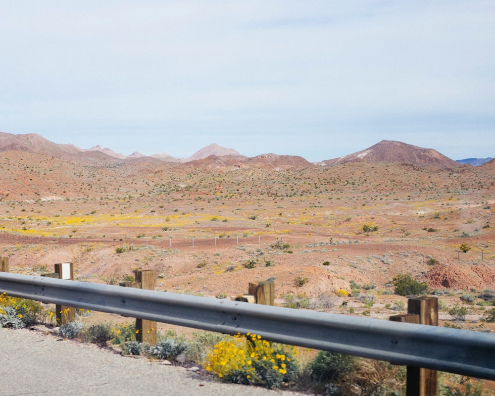 a man riding a motorcycle down a road next to a lush green hillside