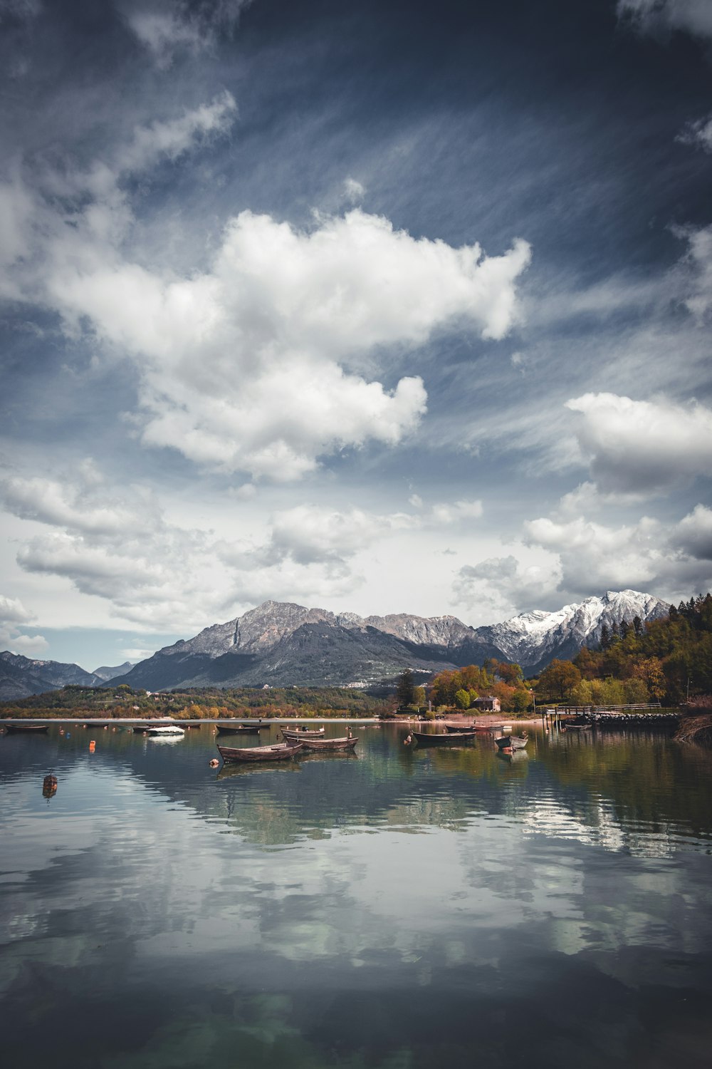 a body of water surrounded by mountains under a cloudy sky