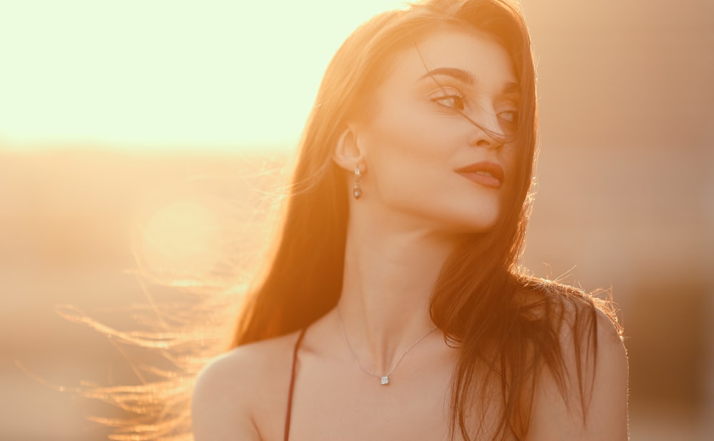 a woman with long hair wearing a necklace and earrings