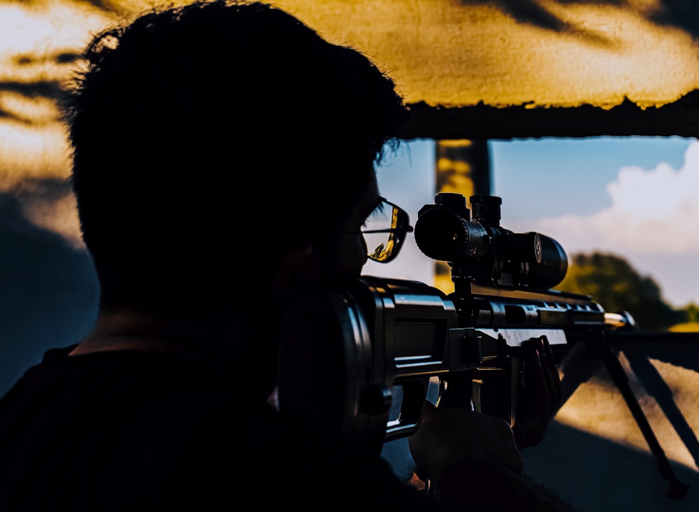 Un hombre sosteniendo un rifle y apuntando a un blanco