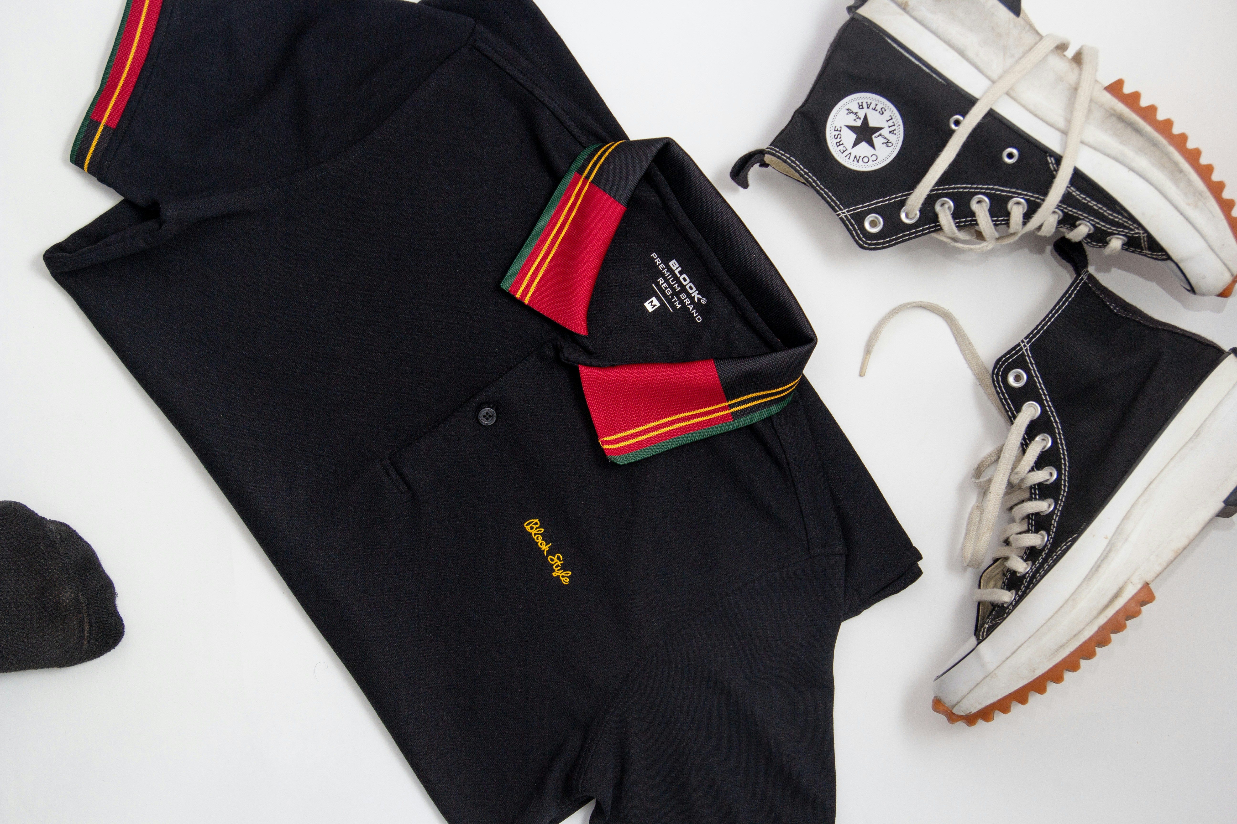 a pair of sneakers, a polo shirt, and a pair of black converse sneakers