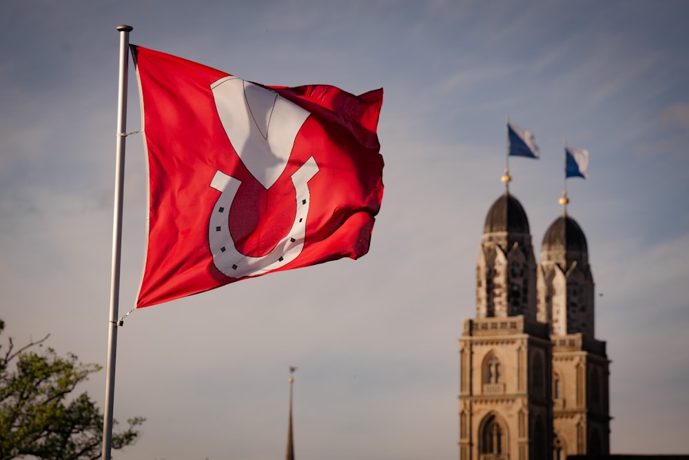 a red and white flag flying in front of a building