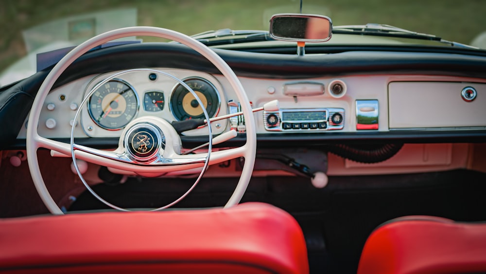 the dashboard of a classic car with red leather seats