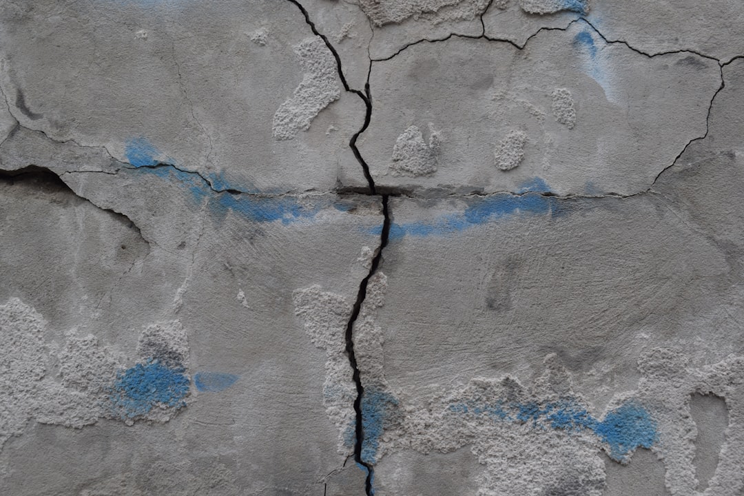 a cracked concrete wall with blue paint on it,