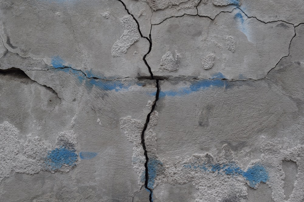 a cracked concrete wall with blue paint on it