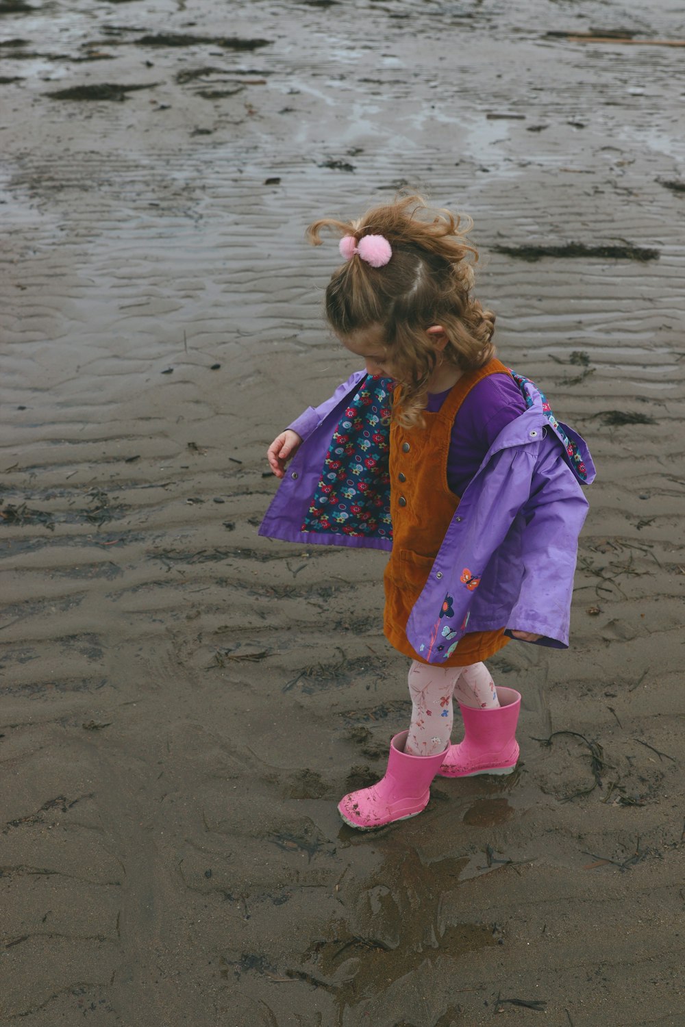 a little girl standing on top of a sandy beach