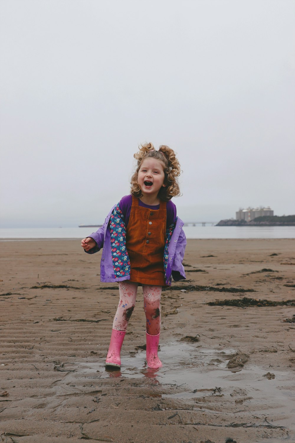 a little girl standing on top of a sandy beach