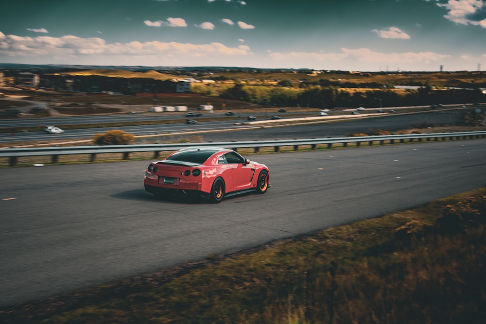 a red sports car driving down a road