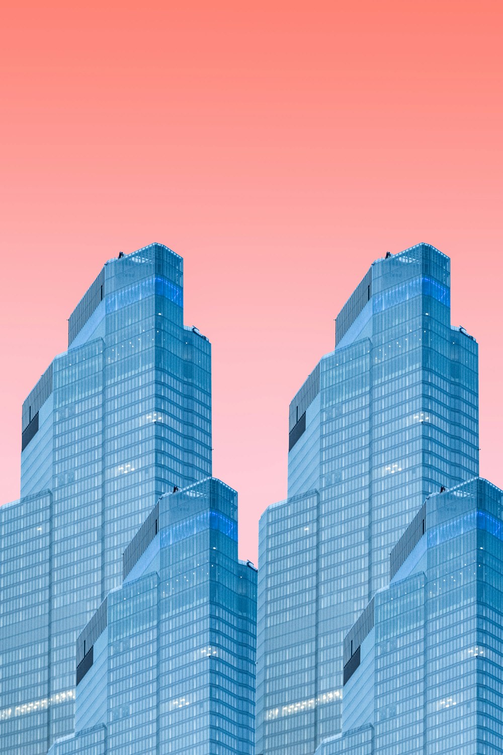 a group of tall buildings with a pink sky in the background