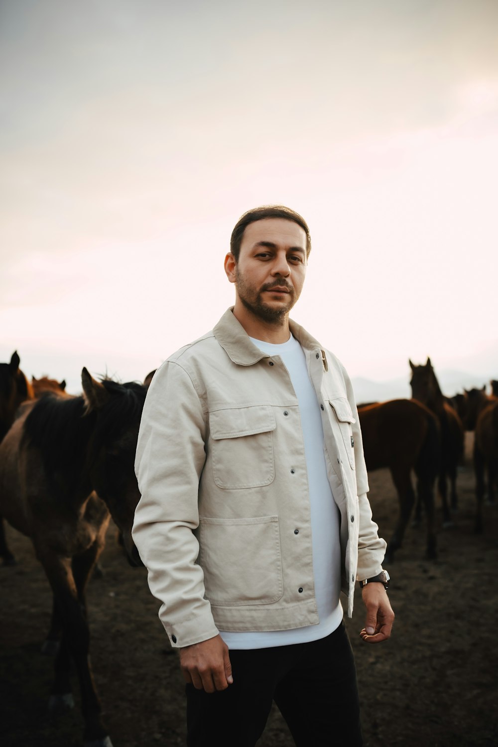 a man standing in front of a herd of horses
