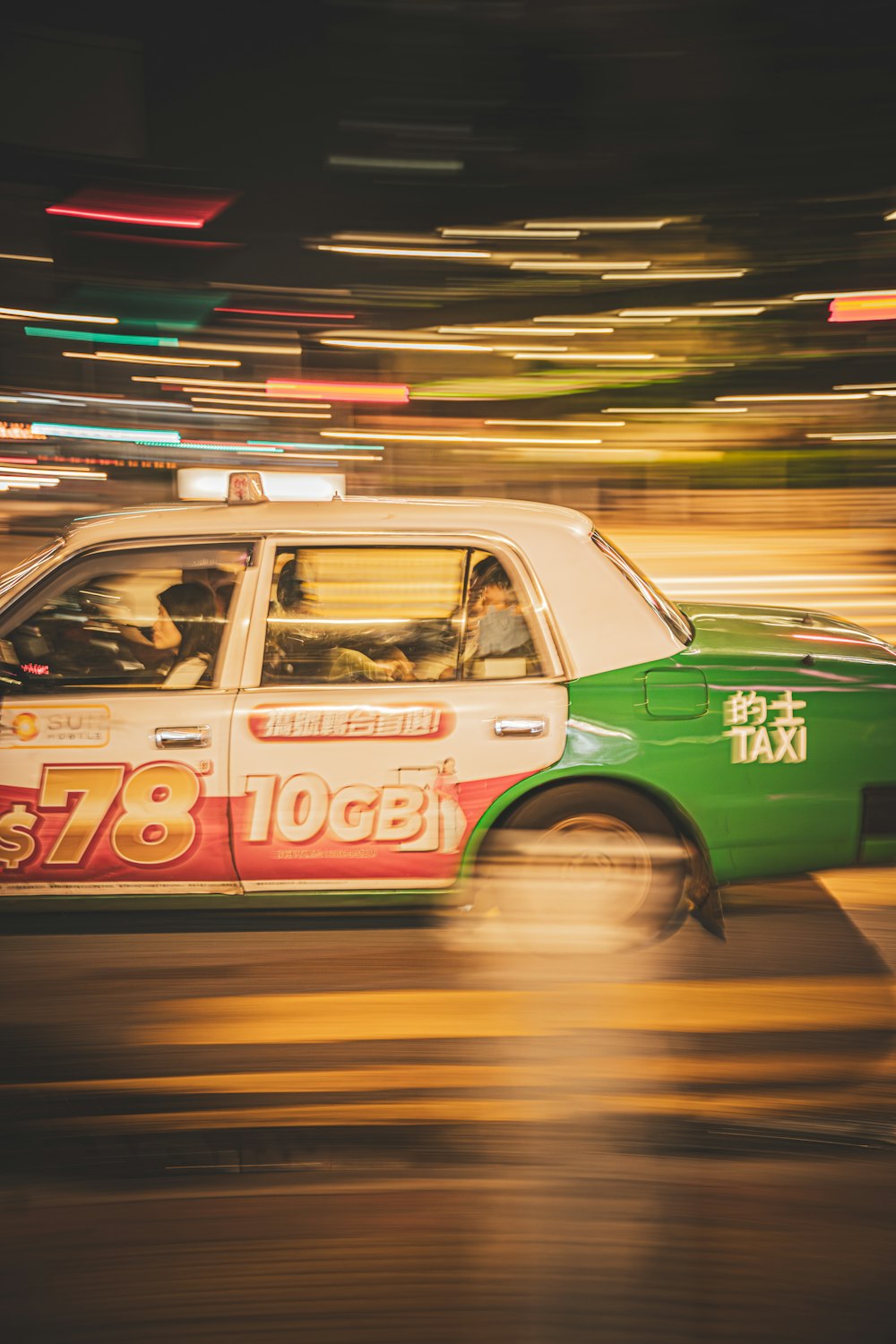 a green and white taxi driving down a street