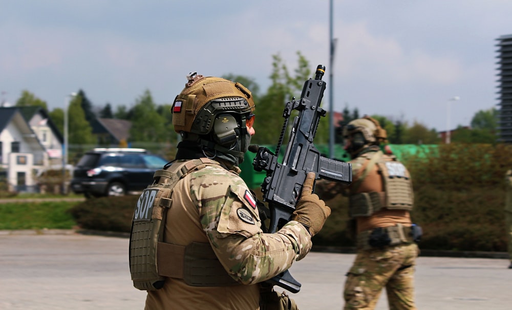 a soldier holding a machine gun in a parking lot