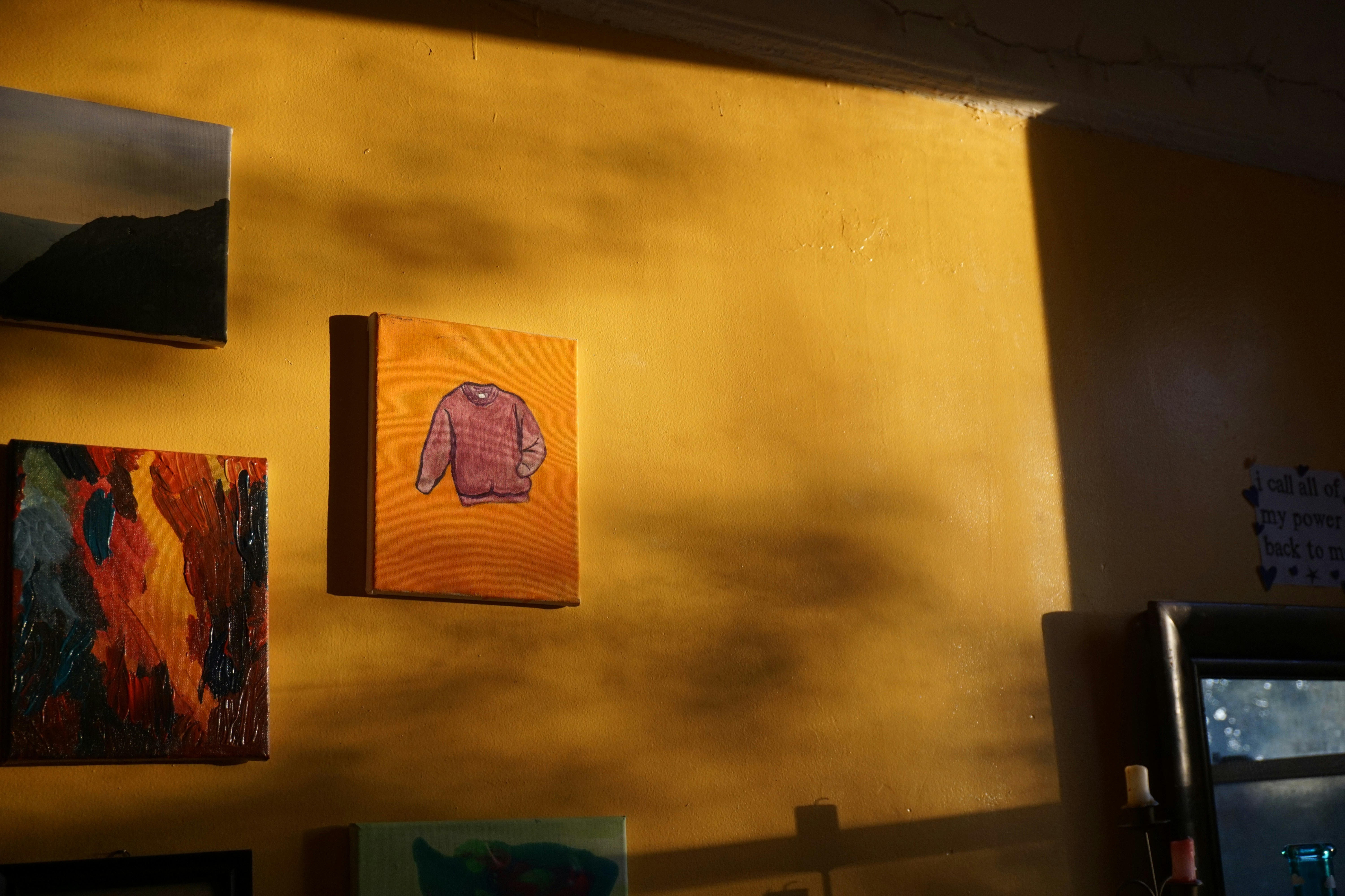 a yellow wall with paintings and pictures on it