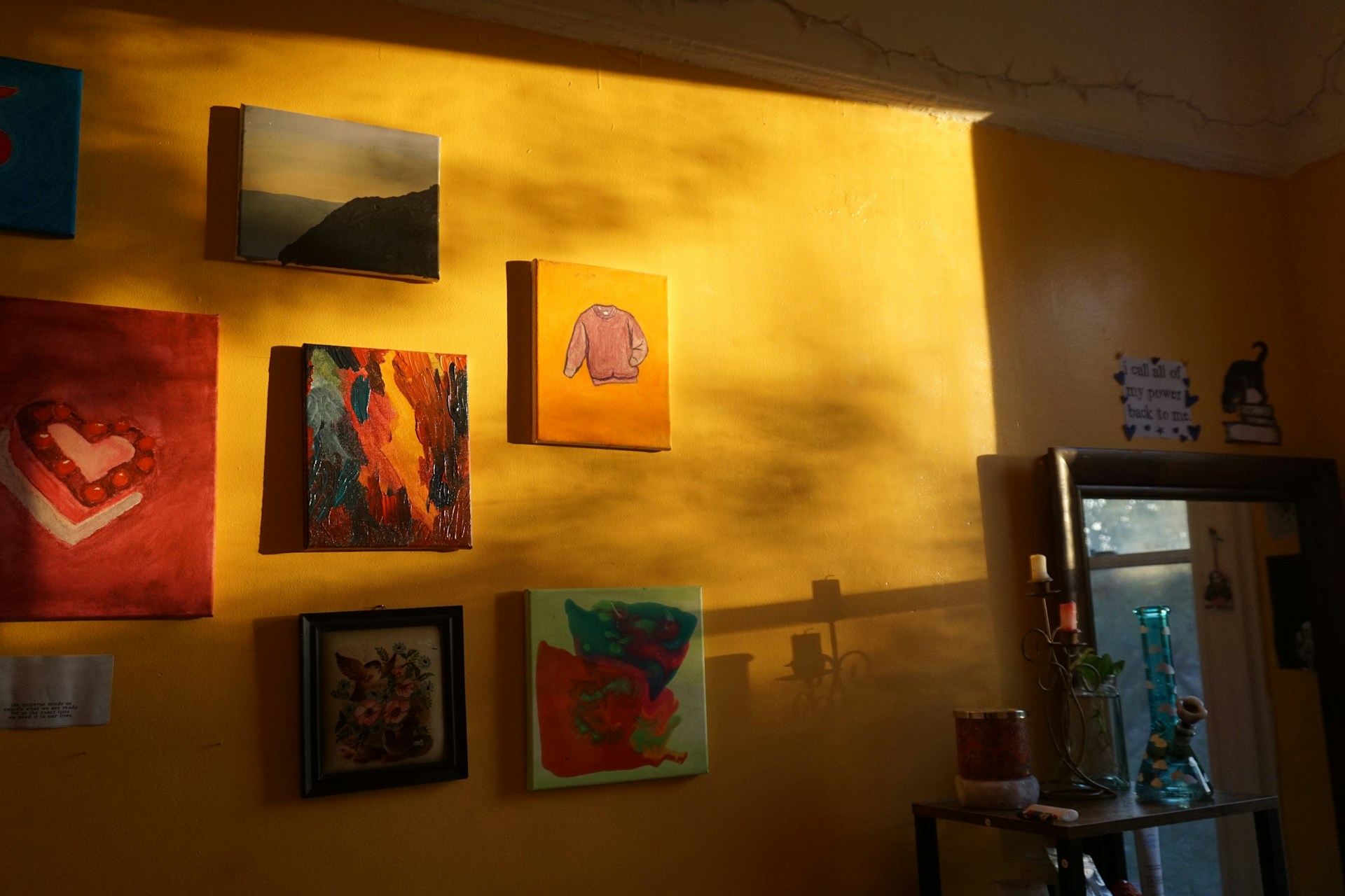 a yellow wall with many paintings on it