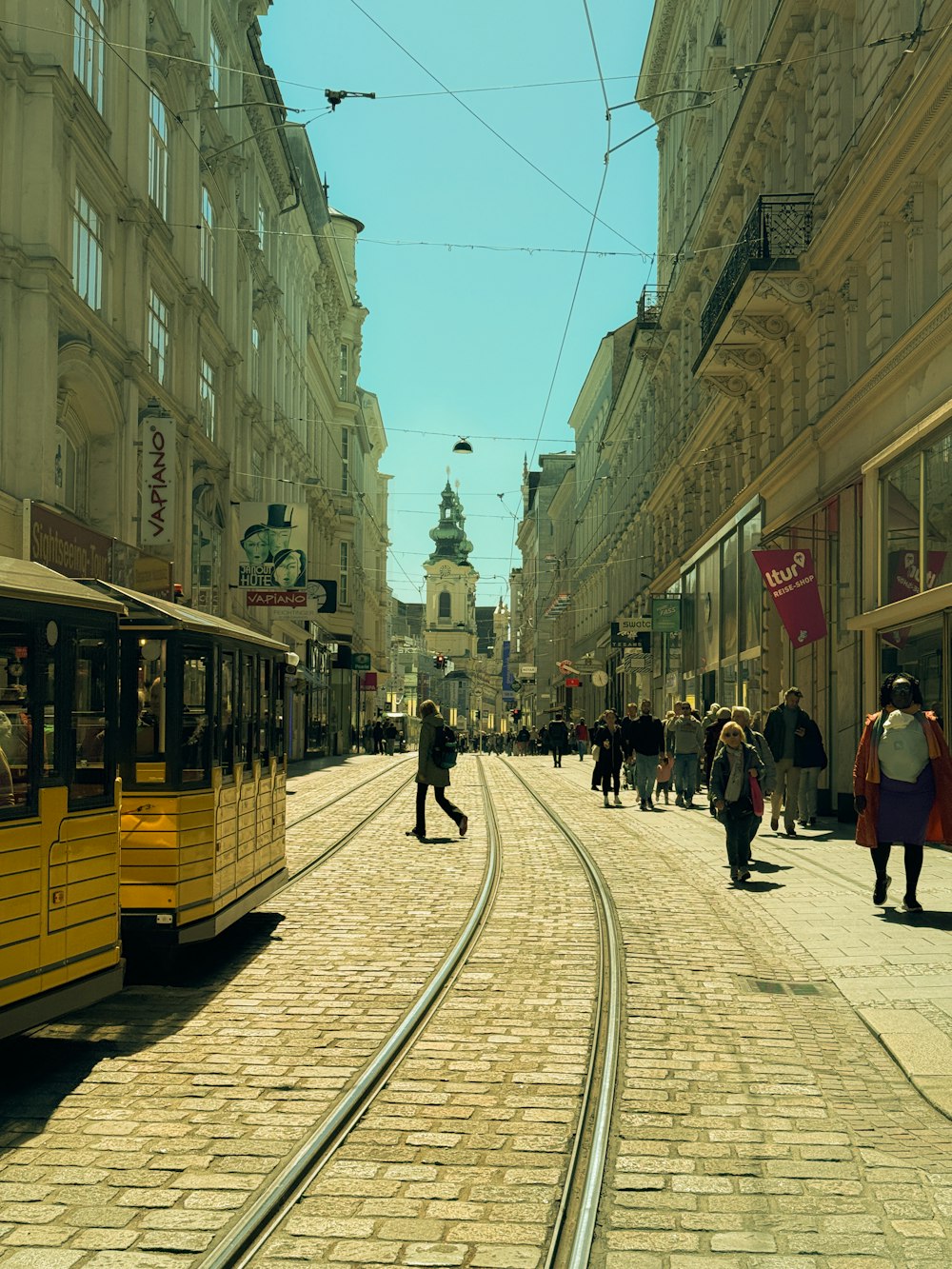 a yellow trolley on a city street with people walking around