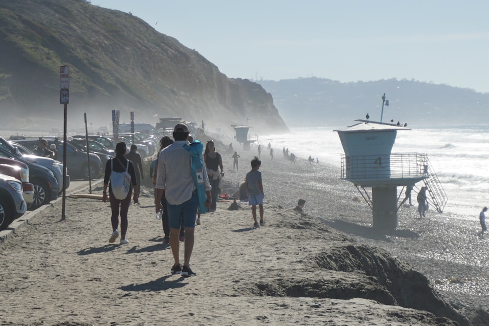 a group of people walking along a beach next to the ocean