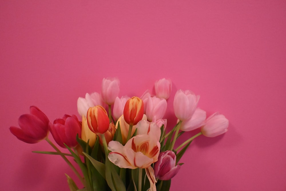 a vase filled with lots of pink and yellow tulips