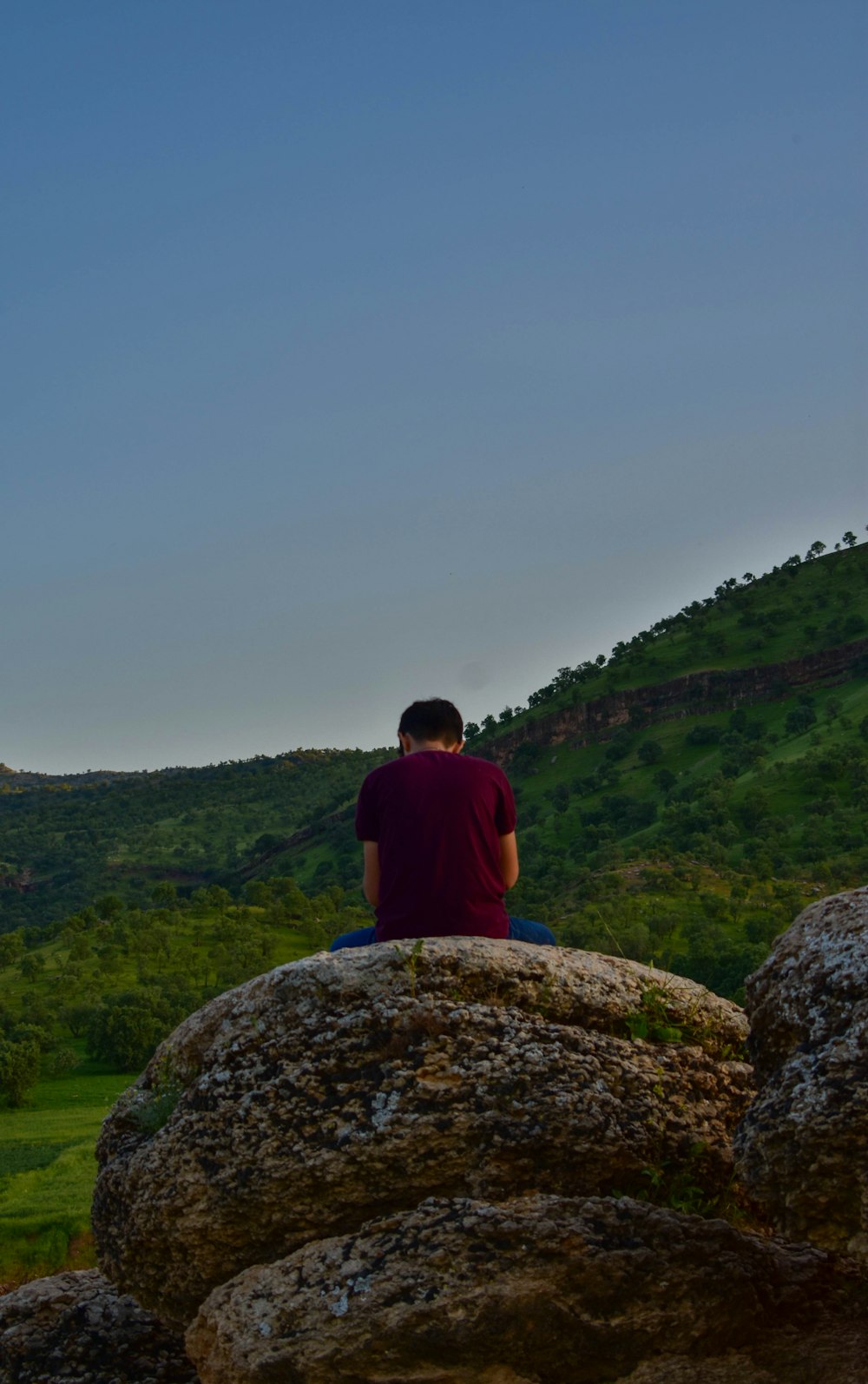 a man sitting on top of a large rock