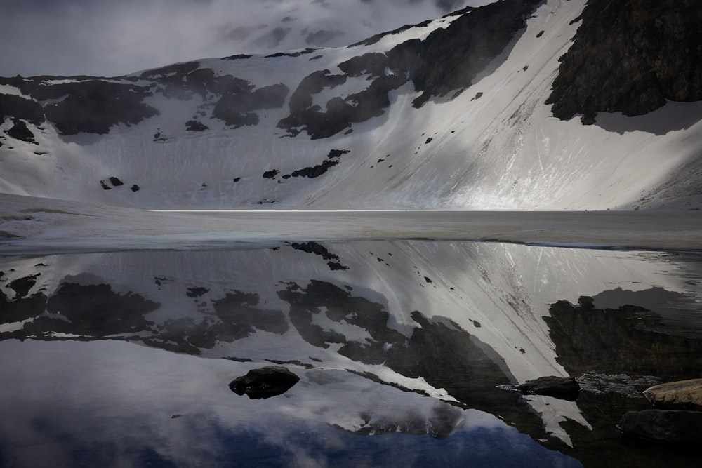 a snow covered mountain with a lake in the foreground