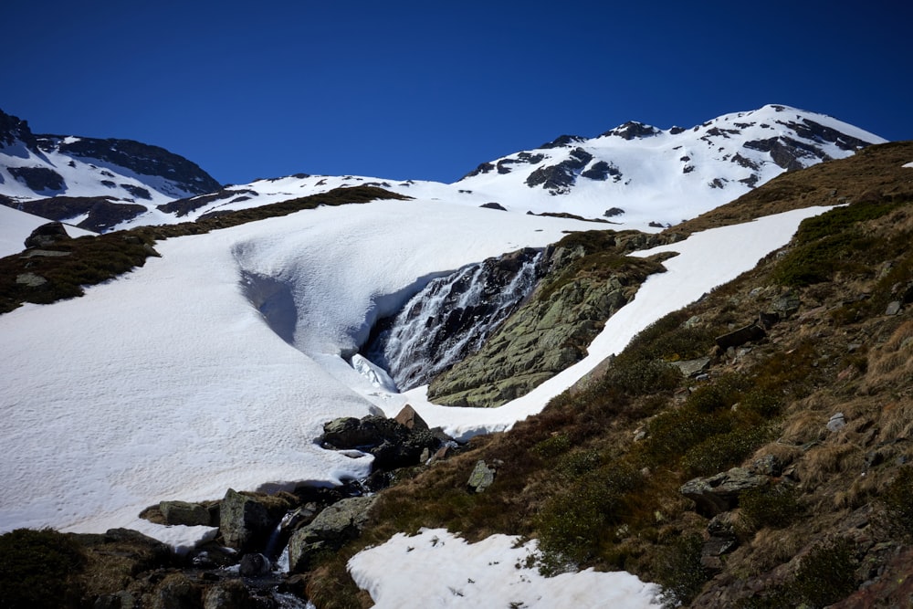 a snow covered mountain with a small stream running through it