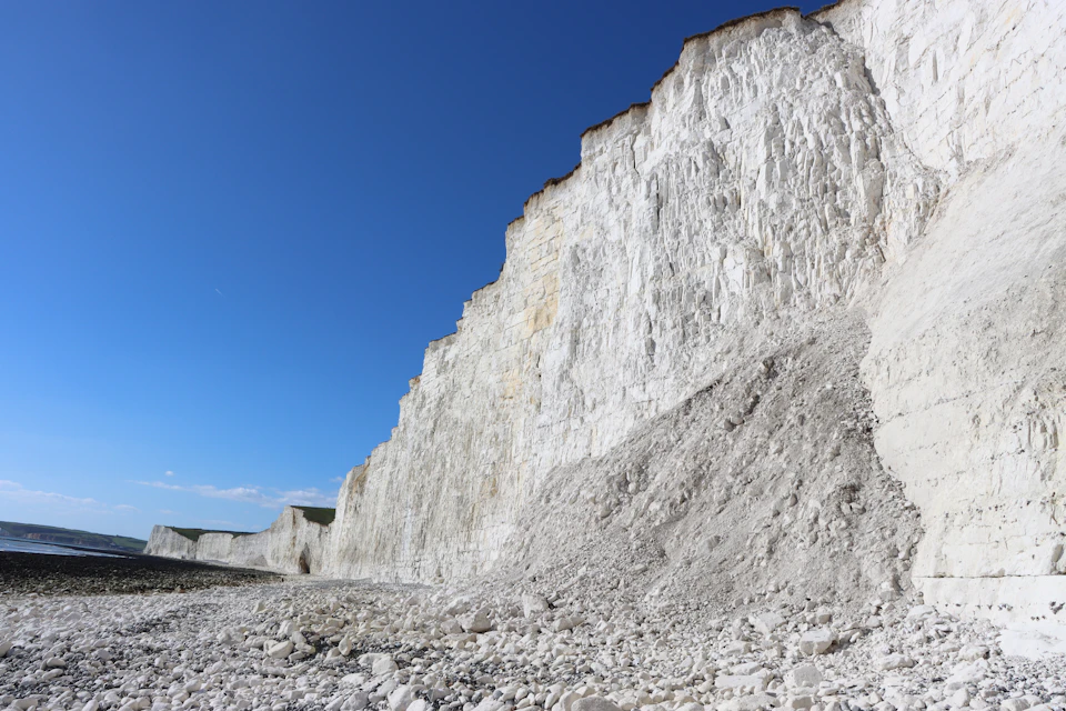 Dramatic cliff face with white chalk cliffs set against clear blue sky landscape