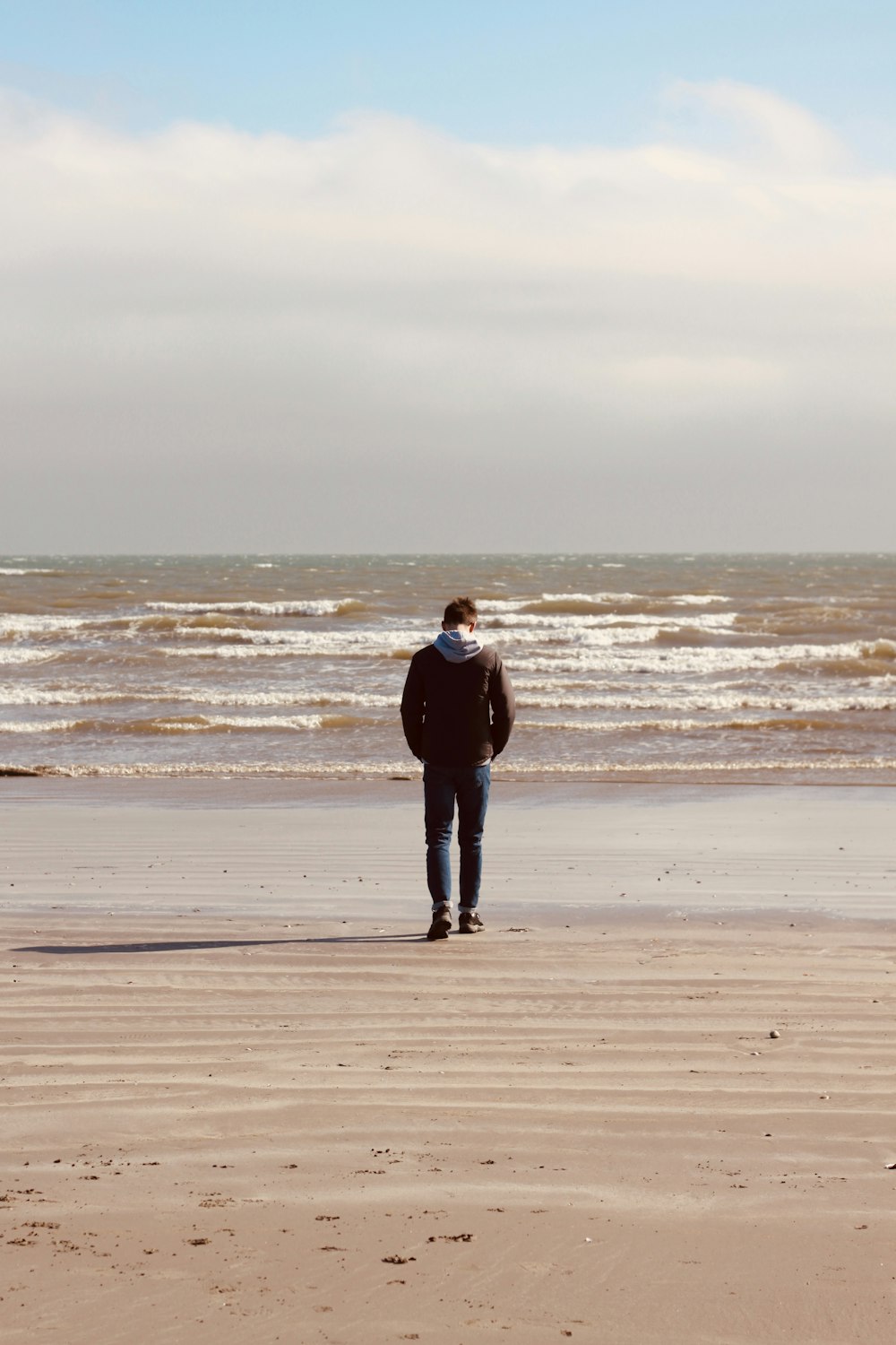 a man standing on a beach next to the ocean