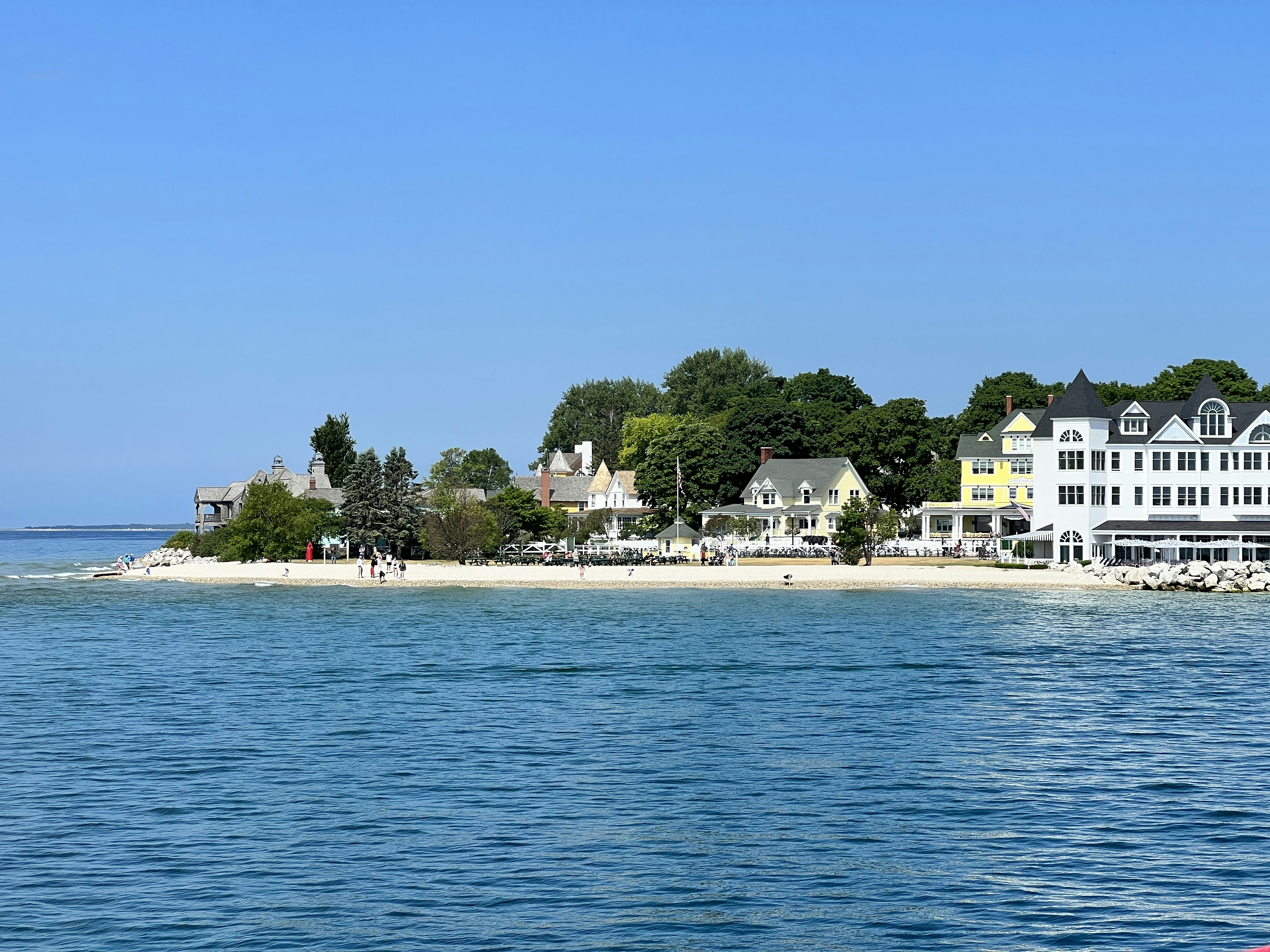 a view of a beach from the water, Shot of a section of Mackinac Island showing the coastline and houses as seen from the ferry.