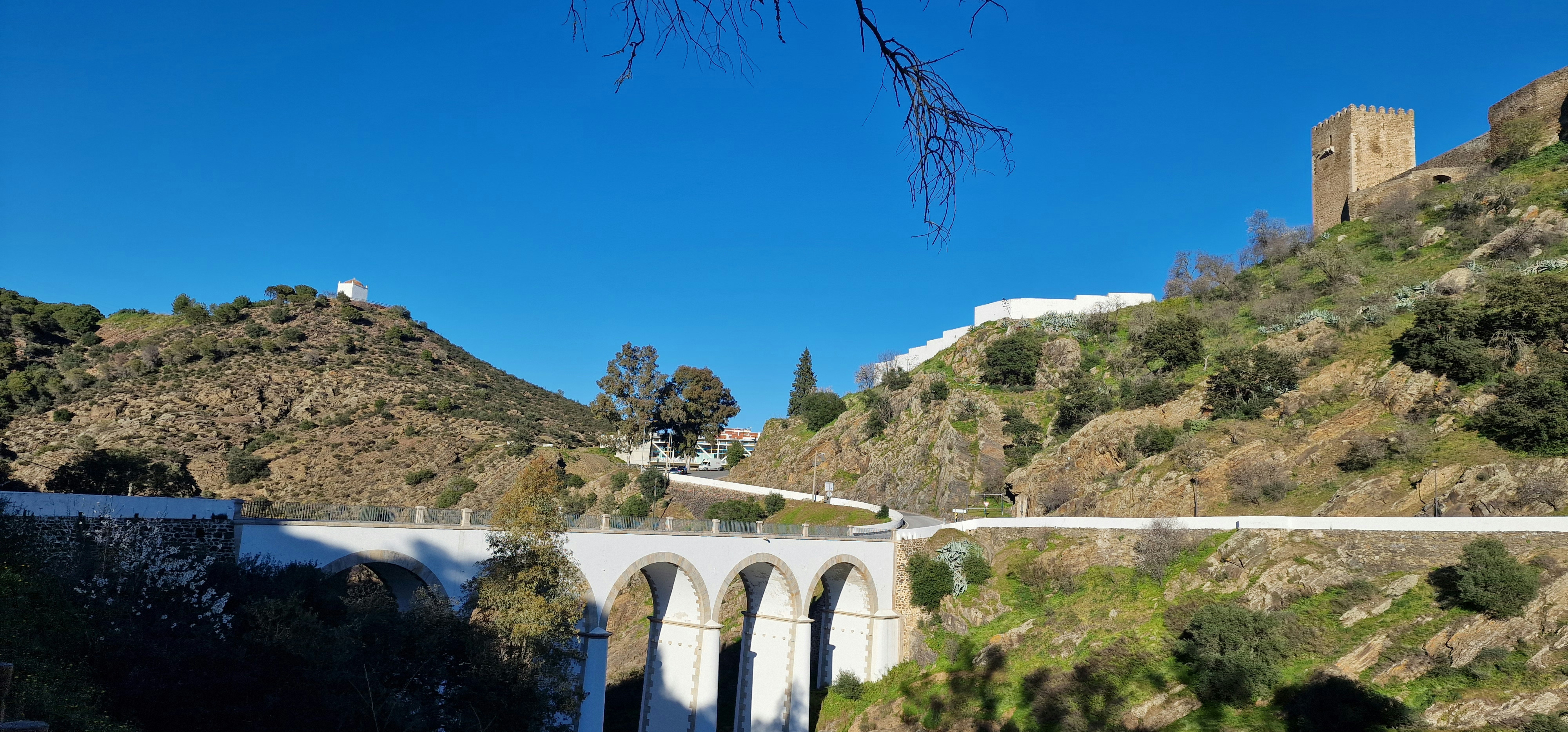 a bridge over a river next to a lush green hillside